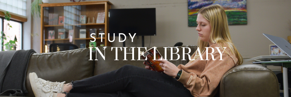 student sitting on a couch and reading a book