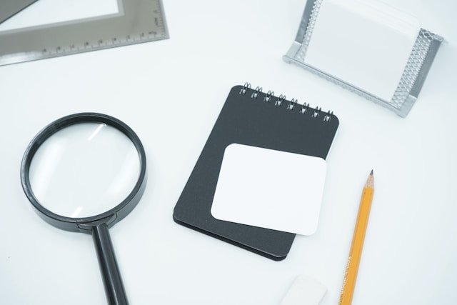 Magnifying glass and notepad, photo by Mediamodifier on Unsplash